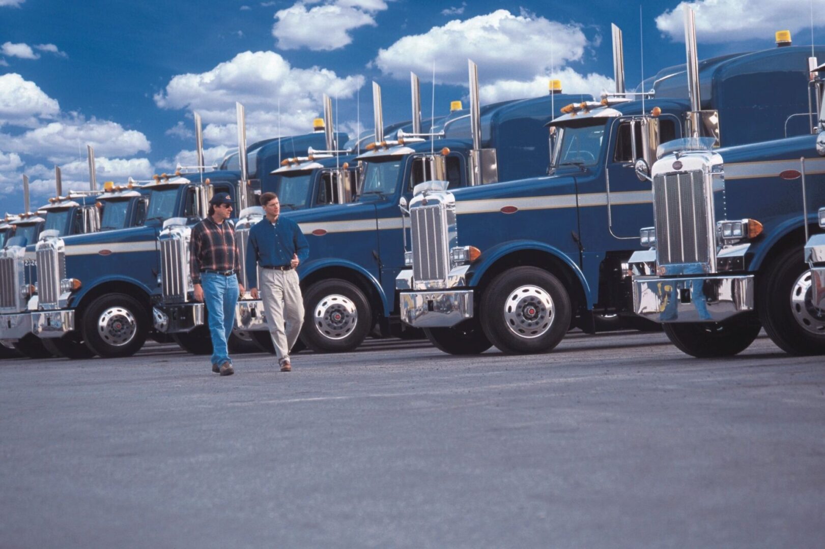 A man standing in front of a row of large trucks.